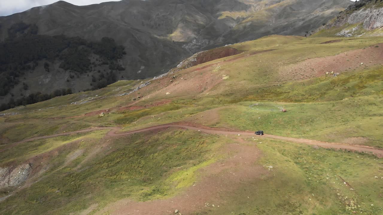 dron video coche montana camino sinuoso gramos soleado inclinar hacia arriba plano general picos distancia