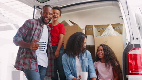 Portrait-Of-Family-Sitting-In-Back-Of-Removal-Truck-On-Moving-Day-Shot-In-Slow-Motion