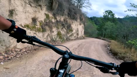 two bicyclists ride their bicycle on a road inside of a forest, hill, and village in guatemala, north america