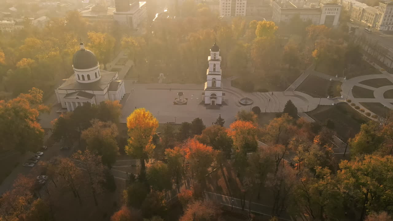 Aerial drone view of Chisinau in autumn at sunset, Moldova. Central park with yellowed trees and people, Cathedral, slow motion