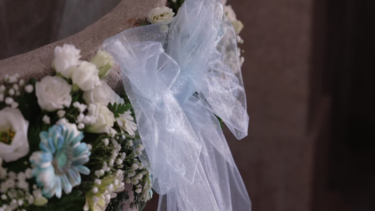white and blue flowers with a sheer bow decorating a stone baptismal font for a ceremony