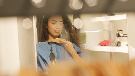 happy, stylish girl trying on outfit in dressing room in interior boutique clothing store with bright lighting.