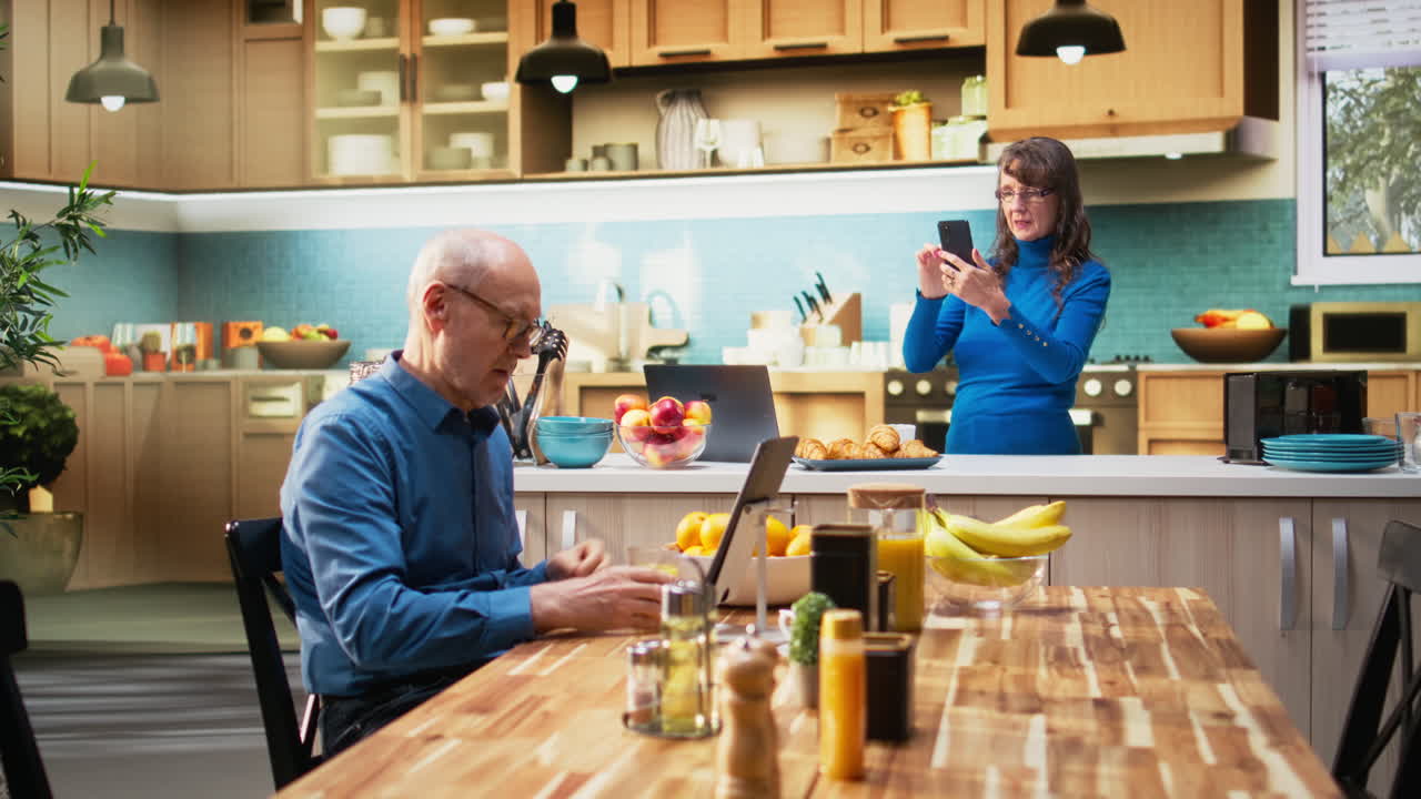 Portrait of elderly natural woman scrolling on smartphone in apartment kitchen