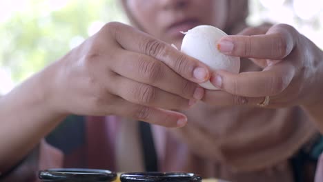 a woman is peeling a hard-boiled egg