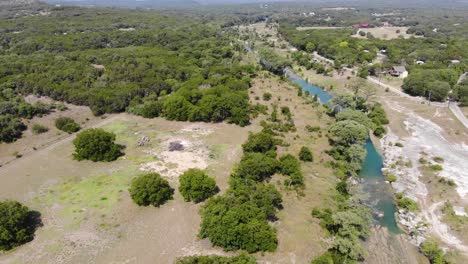 Flying-above-the-fields---trees-over-river-showing-vast-recreational-portion-of-the-river---Aerial-footage-of-the-Blanco-river-in-Wimberly,-TX--Aerial-footage-of-the-Blanco-river-in-Wimberly,-TX