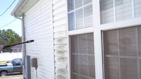 man uses pressure washer to clean house