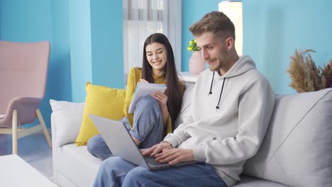 Trabajador-De-Casa,-El-Joven-Esposo-Y-Su-Esposa-Están-Trabajando-Sentados-En-El-Sofá.