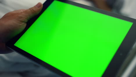 hombre sosteniendo una computadora tablet con pantalla de tecla de croma en la sala de la clínica de cerca.