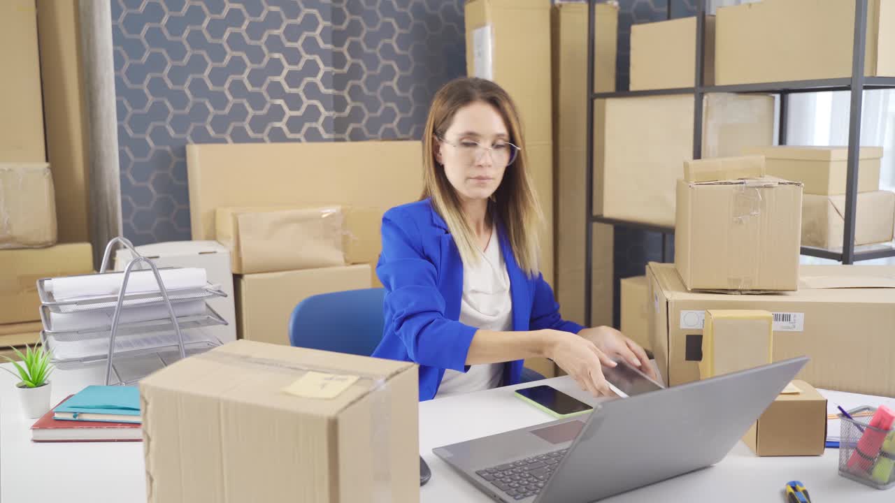 mujer de negocios que trabaja en la computadora y rastrea pedidos en el almacén de embalaje y carga.