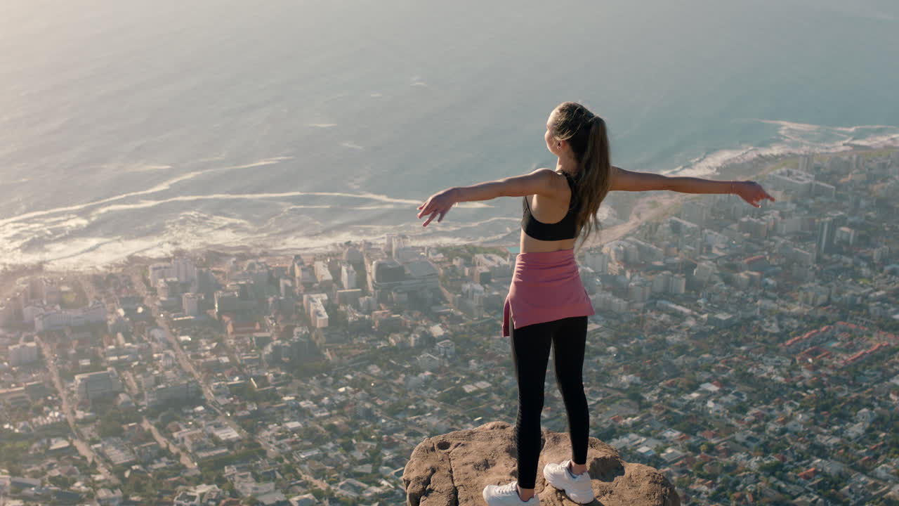 mujer joven con los brazos levantados en la cima de la montaña celebrando el logro niña en el borde del acantilado mirando la hermosa vista disfrutando de viajes aventura libertad
