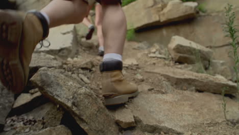 vista inferior de las botas de un hombre excursionista y una mujer, ambos caminando por la montaña