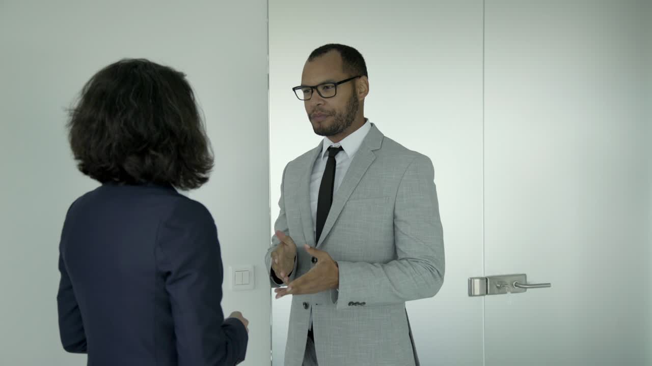 Two business people having conversation in corridor.