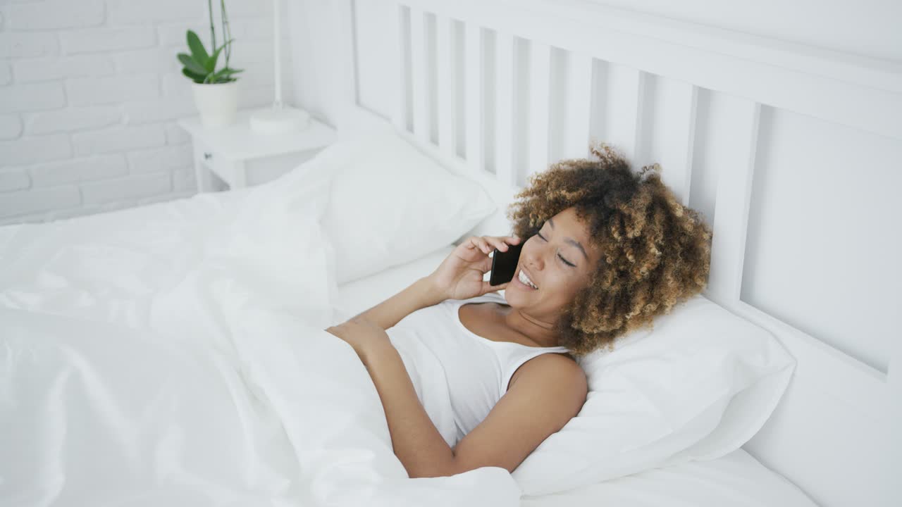 Donna soddisfatta che parla al telefono a letto
