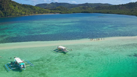 aerial view of a tropical sandbar with traditional boats and tourists in crystal clear waters