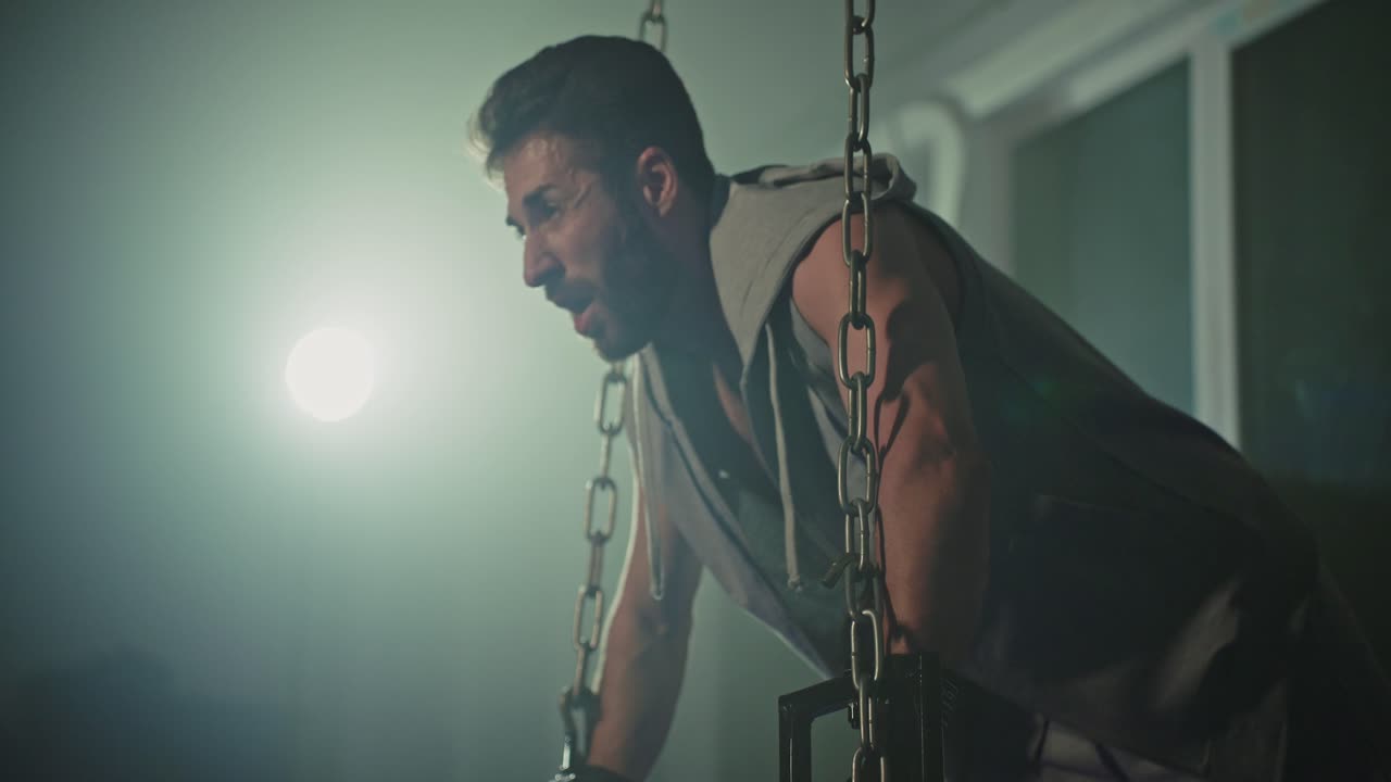 Mand laver pull-ups med kæder i et fitnesscenter