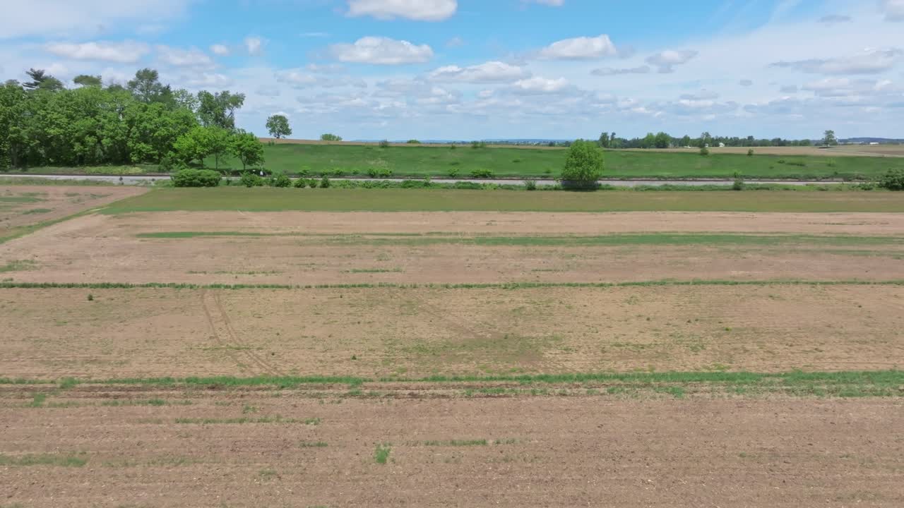 Expansive aerial view of lush green fields and farmlands in rural Pennsylvania under a bright blue sky smooth motion atmospheric lighting rich detail vibrant colors