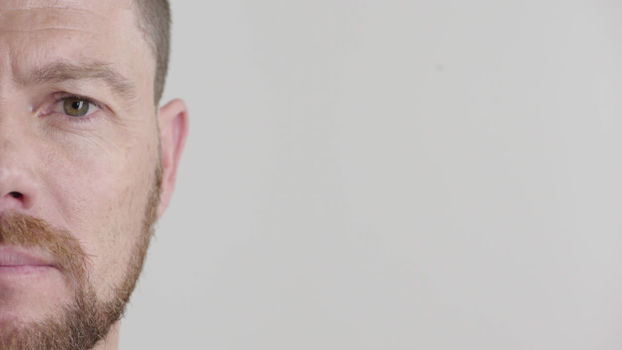 mitad de la cara joven hombre caucásico buscando serio hombre atractivo con barba aislado en fondo blanco