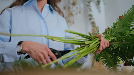 serious florist prepare flowers in shop. woman owner cut flower bouquet.