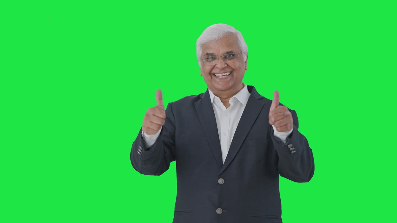 feliz periodista senior indio señalando a la pantalla verde y mostrando los pulgares hacia arriba