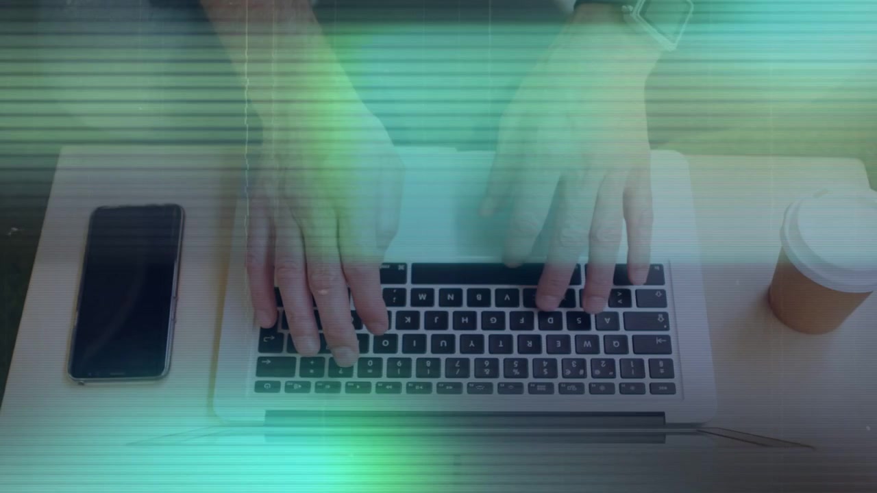 Mand trykker på bærbare taster til arbejde, glitch scanline overlejrer mens hænder taster, telefon, kaffekop.
