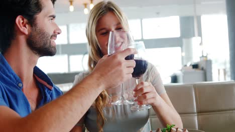 pareja feliz brindando copas de vino mientras comen