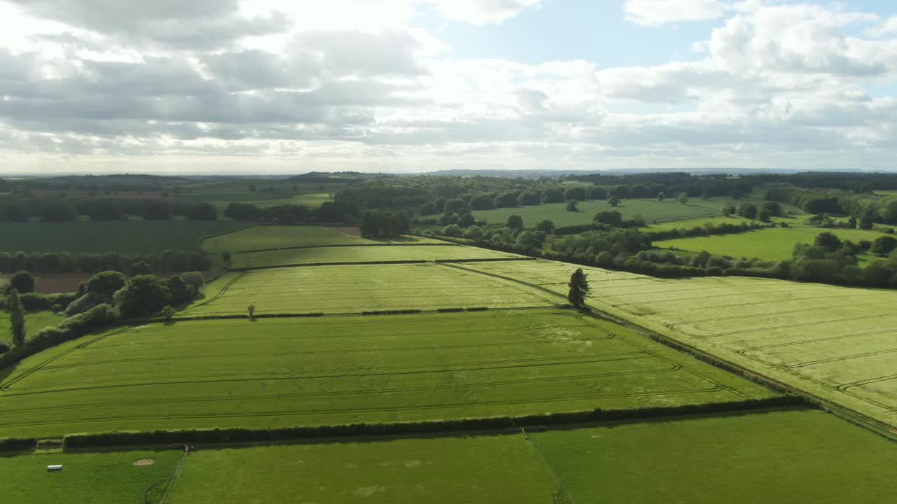 Strong wind blowing across green crop fields causing waves in countryside from drone view