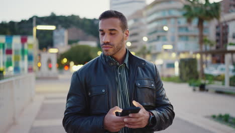 Young-man-using-smartphone-and-walking-outdoors.