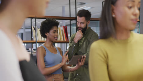 Diverse-male-and-female-business-colleagues-talking-and-using-tablet