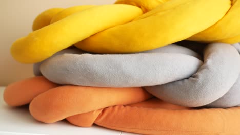 braided fabric pillows in yellow, grey, and orange