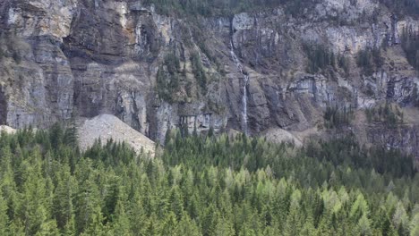 Drone-flight-over-a-beautiful-alpine-valley,-waterfalls-and-high-snow-capped-mountains