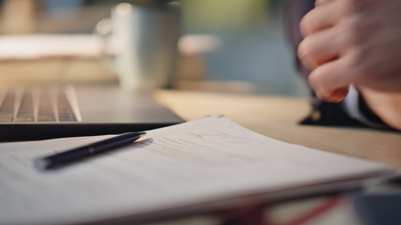 Closeup hand signing document at desk with ballpen. Unknown businessman working