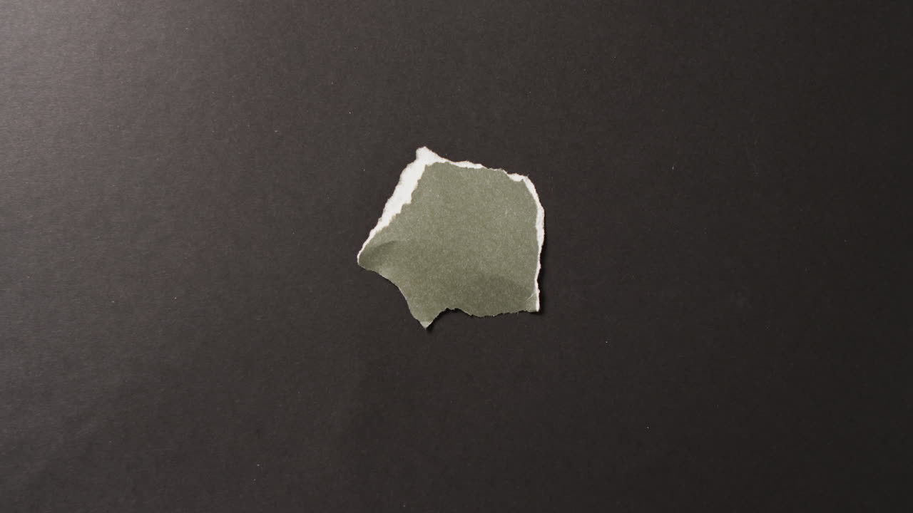 video de primer plano de un pedazo de papel verde roto sobre un fondo negro