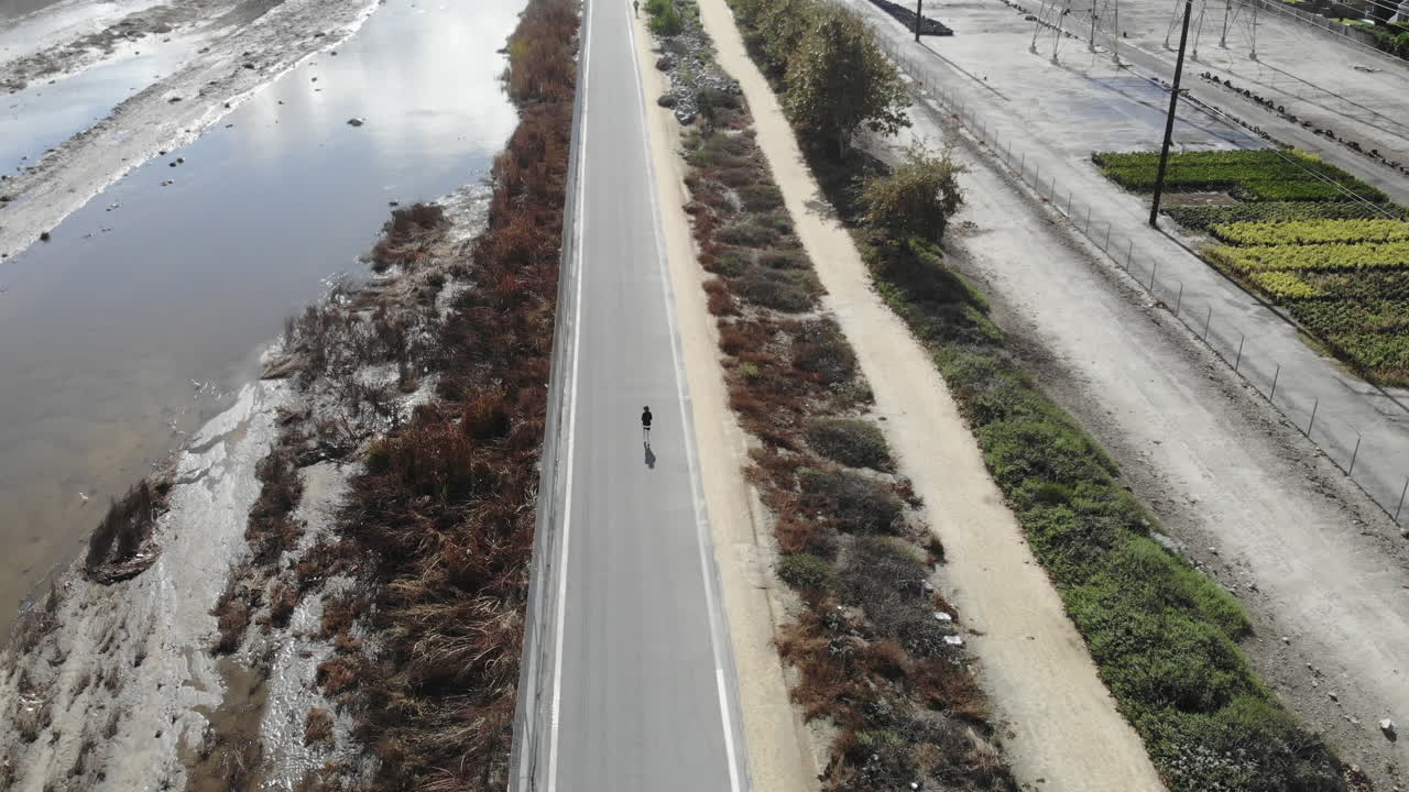 A 4K aerial drone of a young boy as he runs along the riverbed for his daily workout.
