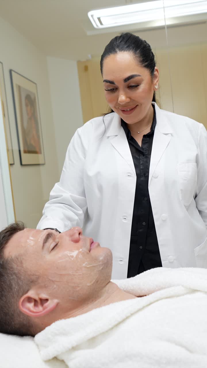 Woman Aesthetician Applying Facial Treatment to Man's Face in Clinic