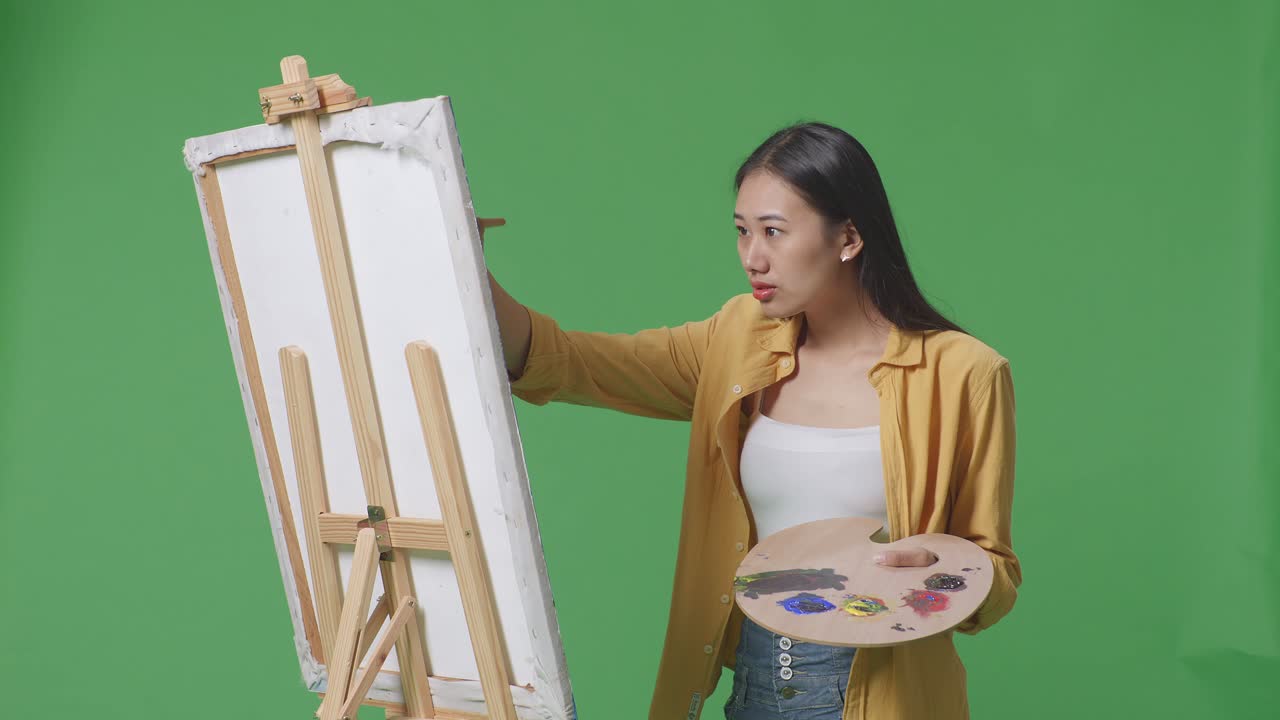 팔레트 를 가진 캔버스 에 그림 을 그리는 여자