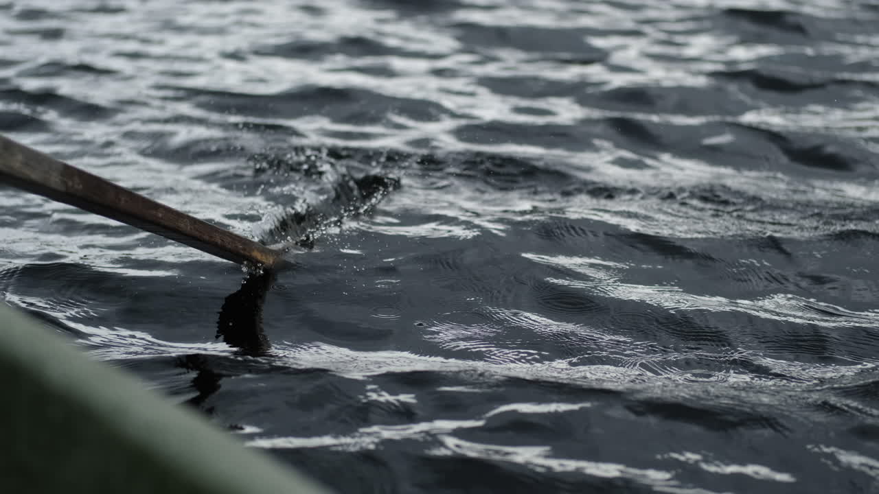 Oar of a row boat hitting calm waters