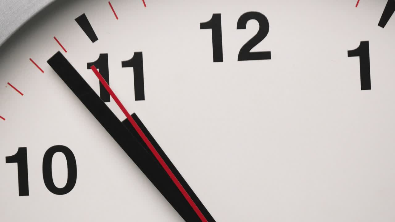 Close-up white wall clock show the time at 11o'clock.