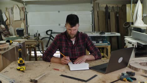 woodworker taking notes in his workshop