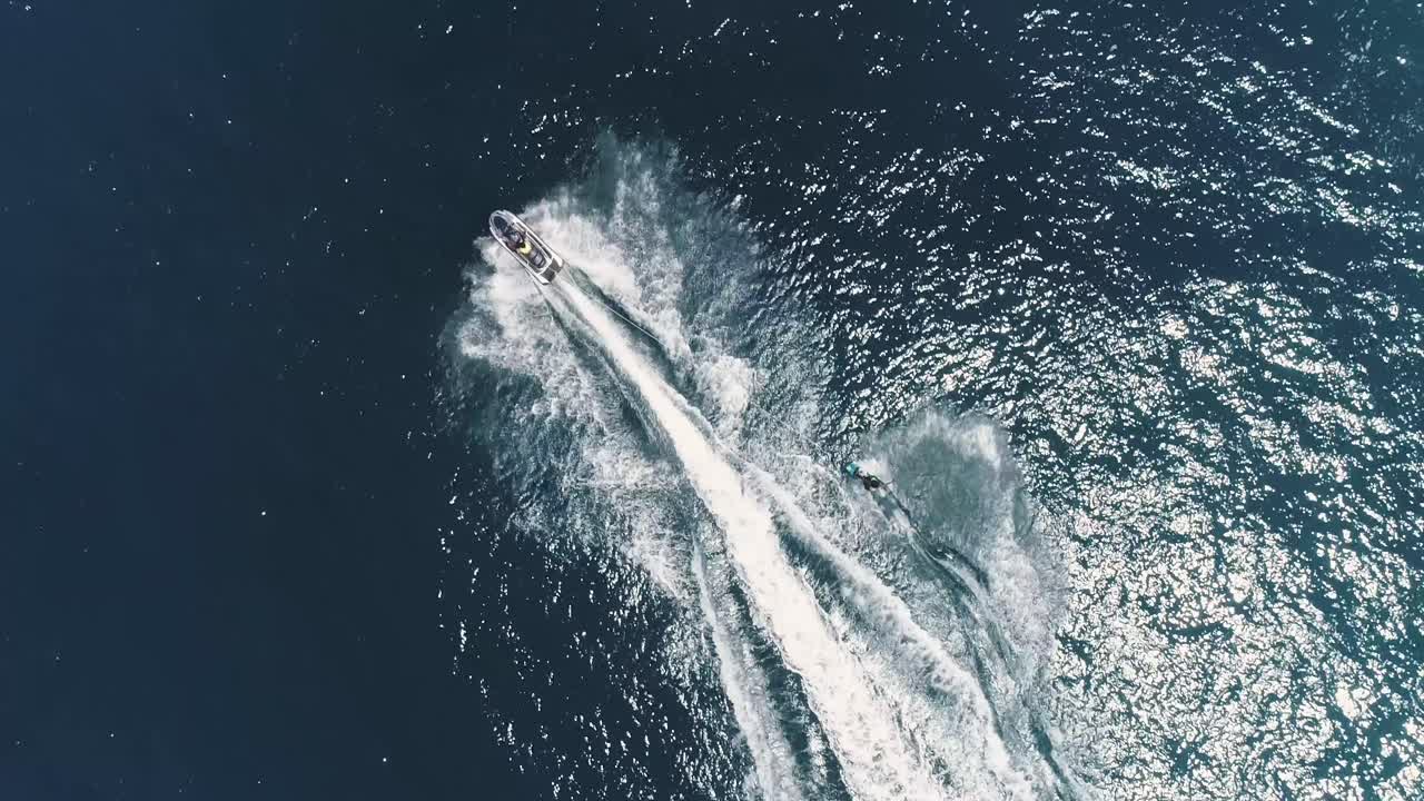 熱帯の青と緑の海の水景でジェットスキーに乗るジェットスキーとサーフライダー。波が立つ海でのスポーツ活動を上空から撮影した映像。美しくアドレナリンが湧き出るエクストリームスポーツの光景