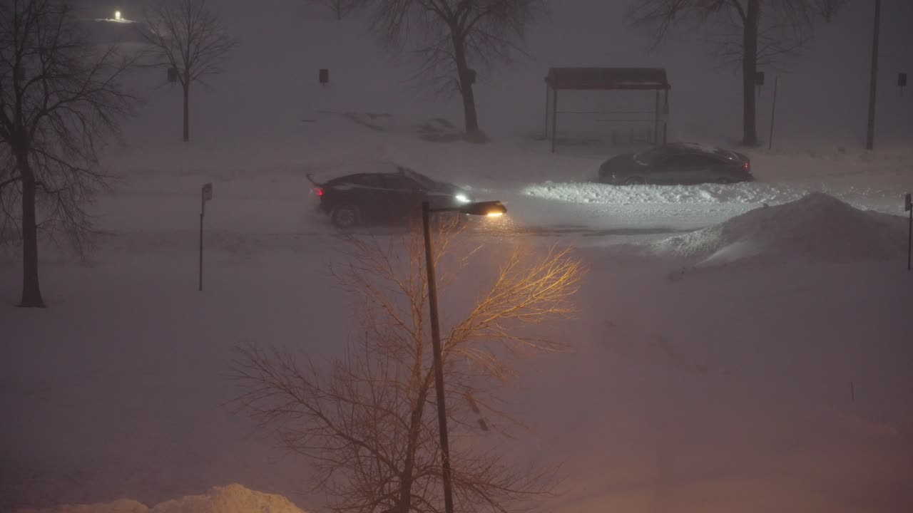 Car passes tungsten street light pole under heavy snow