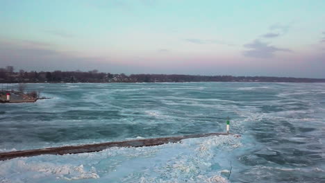 a sweeping shot over a lighthouse on a pier reveals miles of ice over a vast frozen lake