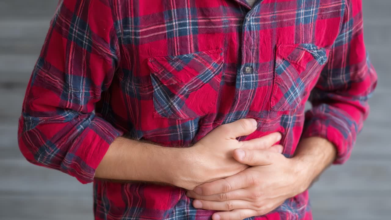 A person clutches their stomach, demonstrating discomfort or pain, possibly indicating an issue related to digestion or health concern affecting their well-being