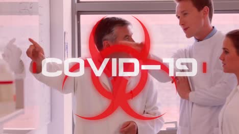 Das-Wort-„Covid-19“-Steht-Auf-Einem-Gesundheitsgefährdungsschild,-Im-Hintergrund-Arbeiten-Wissenschaftler