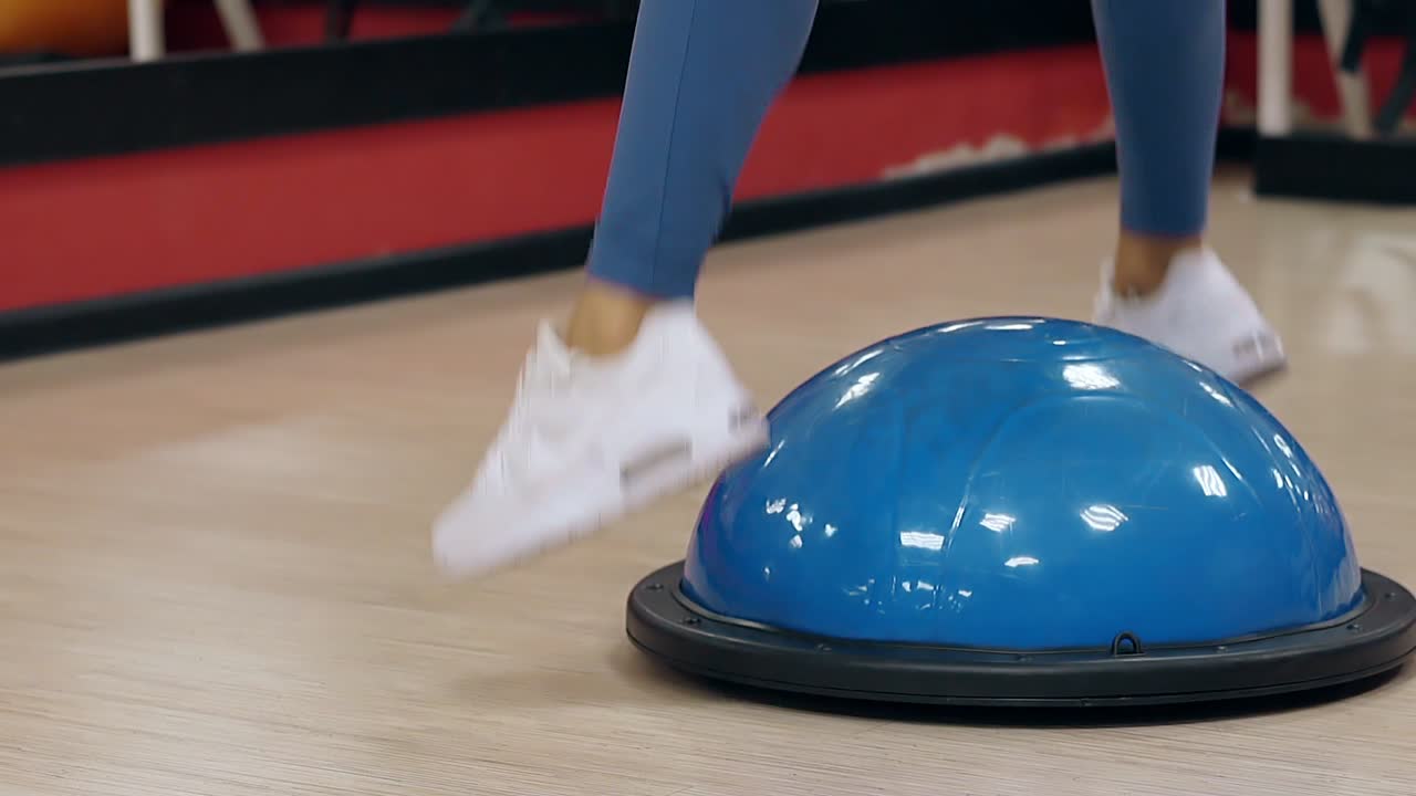 cámara lenta vista de cerca chica piernas delgadas saltar en la pelota de estabilidad