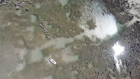 Panning-Over-Beach-Side-Tide-Pools-with-Crystal-Clear-Water-at-Low-Tide-Panning-over-Single-White-Boat