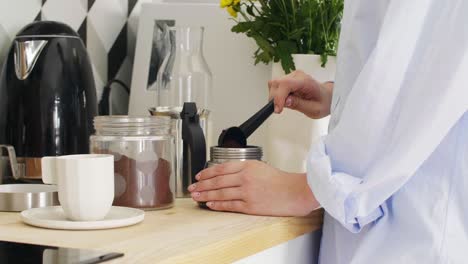 part of woman making coffee in her kitchen