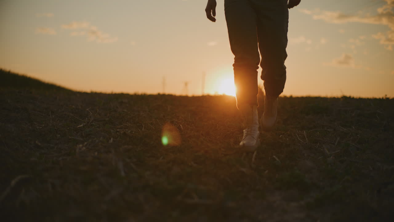 Person Walking Towards Sunset in Field