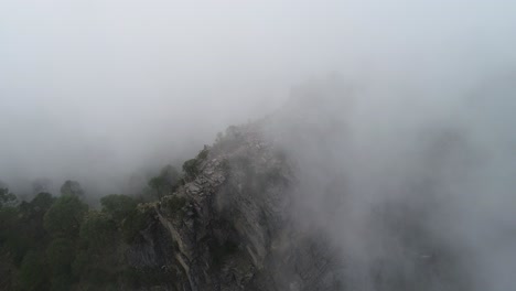 aerial pan of mountain peak in mexico being engulfed by grey dark rain clouds