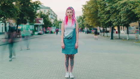 woman with pink dreadlocks and tattoos on a city street