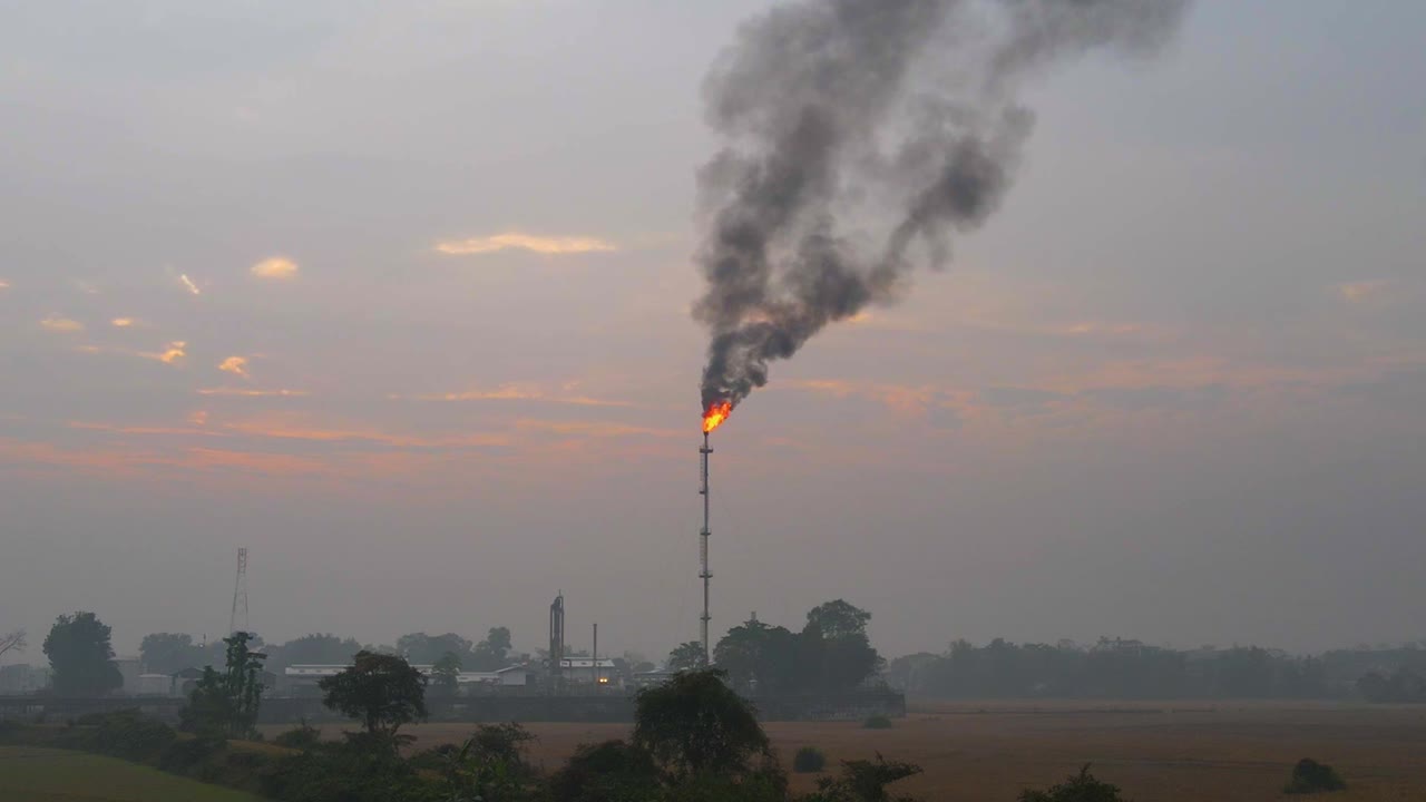 안개가 자욱한 농업 농지 위의 정유소 불타는 플레어 스택 흡연을 향한 조감도 현기증 효과